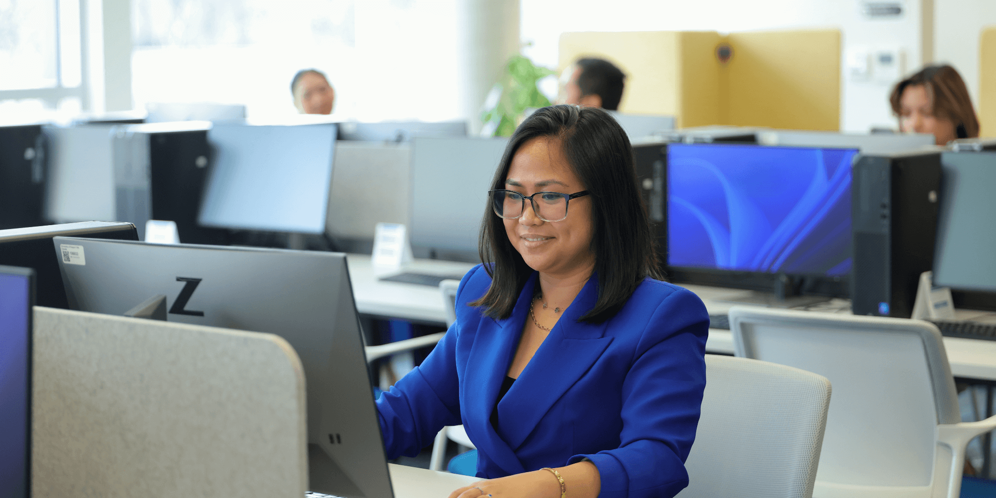 A woman smiling in front of a desktop computer