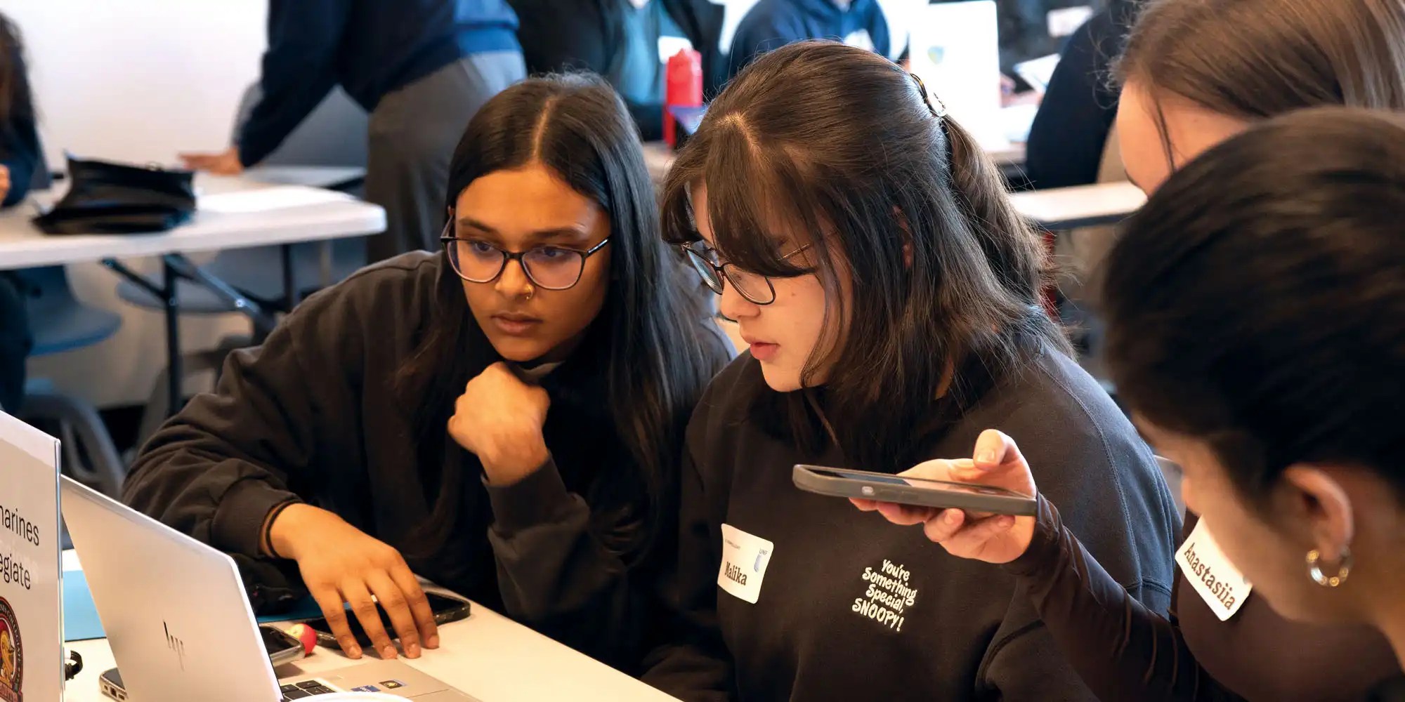 UNF students looking at laptop screen and pointing at it